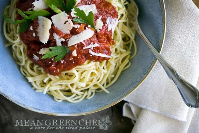 A bowl of spaghetti topped with Authentic Italian Red Sauce, sprinkled with parsley and shaved Parmesan cheese, served in a rustic blue pasta bowl.