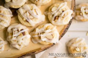 Overhead photo of Almond Pastry Cookies on white wooden background with roasted almonds sprinkled around.