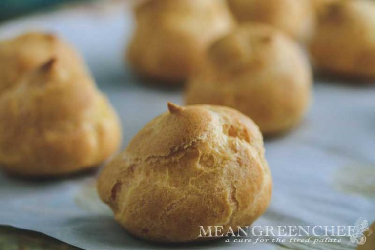 Pate a Choux Pastry baked to a golden brown sitting on a sheet pan lined with parchment paper.