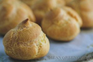 Pate a Choux Pastry baked to a golden brown sitting on a sheet pan lined with parchment paper.