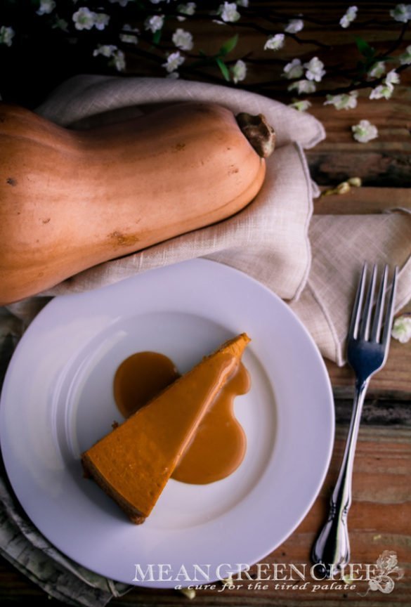 Pumpkin Spice Cheesecake with Caramel Sauce Recipe on a white plate sitting on a rustic wooden background.