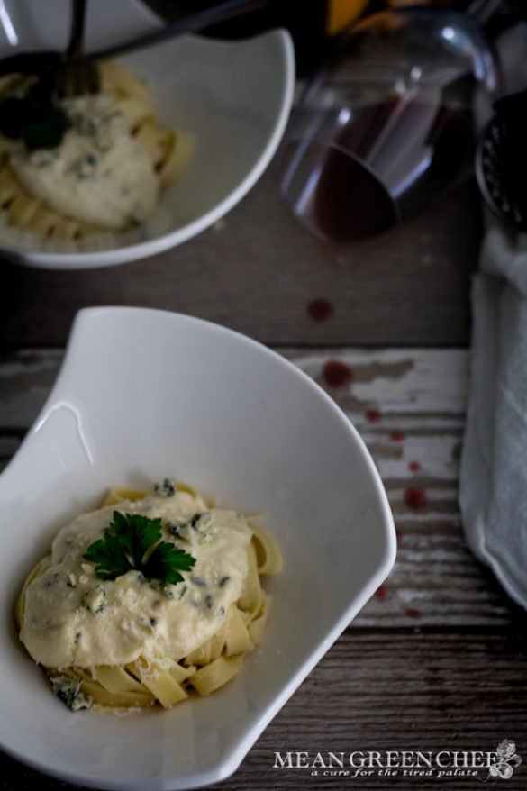 White bowls of pasta Alfredo with a glass of spilled red wine.
