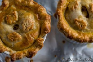 Overhead photo of two large double crust chicken pot pies in white ramekins on a baking sheet lined with foil.