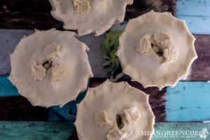 Overhead photo of four large double crust chicken pot pies in white ramekins on a blue wooden background.