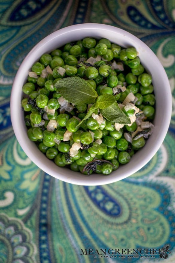 Minted Peas with Lemon and Shallots in a white bowl on a paisley background.