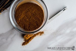 Small glass bowl with apple pie spice on a white marble background. Mean Green Chef