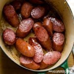 Overhead photo of smoked sausage in a green Dutch Oven for Dutch Stamppot. Mean Green Chef