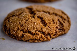 Freshly baked Best Ever Molasses Cookie close up showing crispyness of the outside of the cookie. Cooling on parchment.