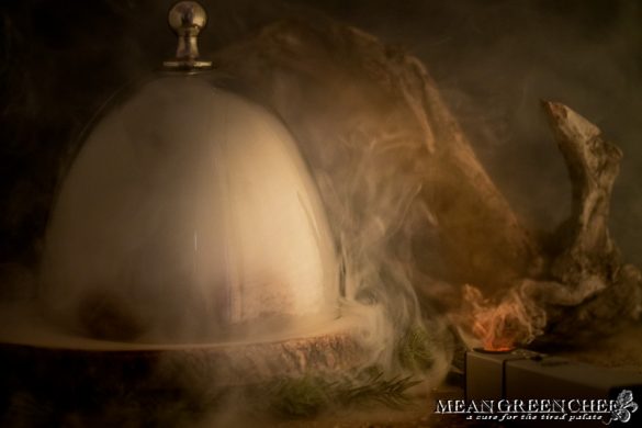 Portobello mushrooms smoking with bourbon wood under a glass dome.