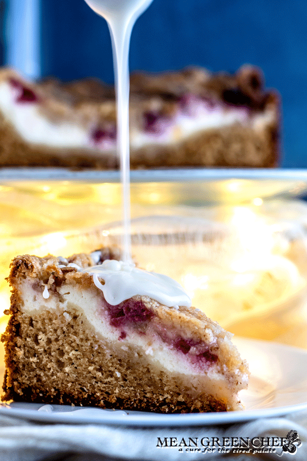 Side photo of Raspberry Coffee Cake with thick vanilla glaze being poured over top.