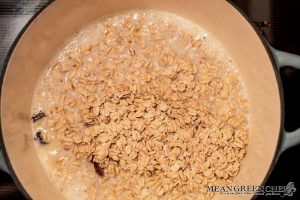 Ingredients for Spiced Mandarin Pecan Oatmeal cooking in a pot on the stove top.