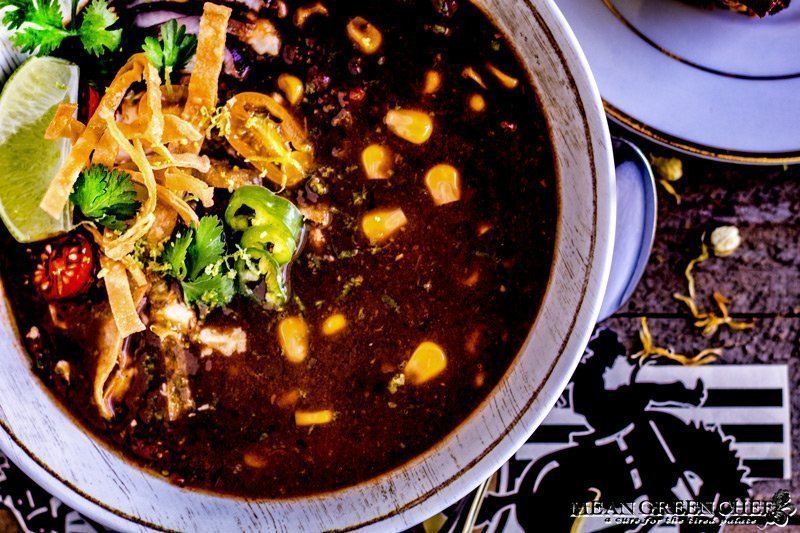 Close up shot of a bowl of Black Bean Soup garnished with crispy tortilla strips.