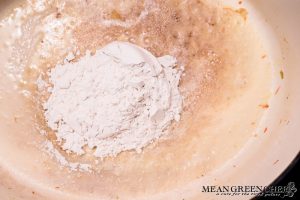 Flour being added to a large dutch oven to become a golden roux for Bistro Broccoli Cheese Soup.