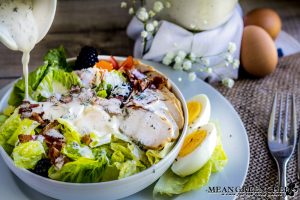 Herbed Buttermilk Ranch Dressing being poured over a chicken bacon ranch salad