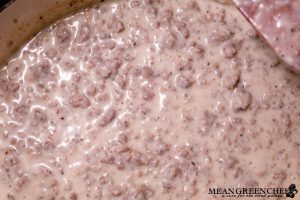 Country Sausage Gravy being made in large gray dutch oven on the stove top.