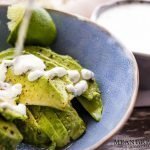 Cilantro Garlic Sauce being poured over freshly sliced avocado.