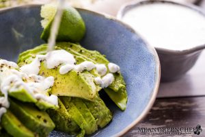 Cilantro Garlic Sauce being poured over freshly sliced avocado.