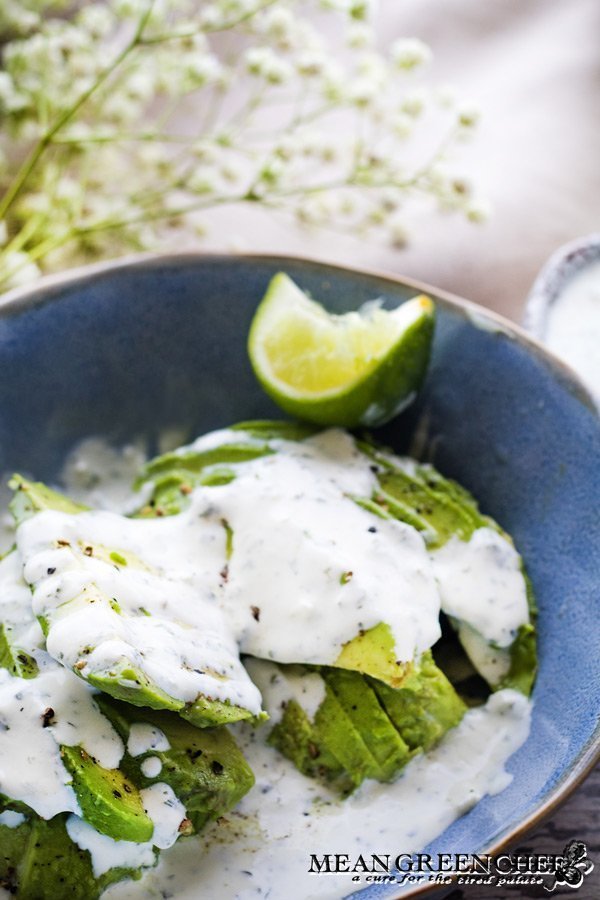 Cilantro Garlic Sauce over freshly sliced avocado in a blue bowl.