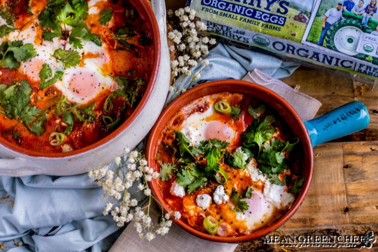 Shakshuka in terracotta pots on a rustic wooden background.