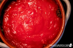 Tomato sauce being added to pot for Shakshuka.