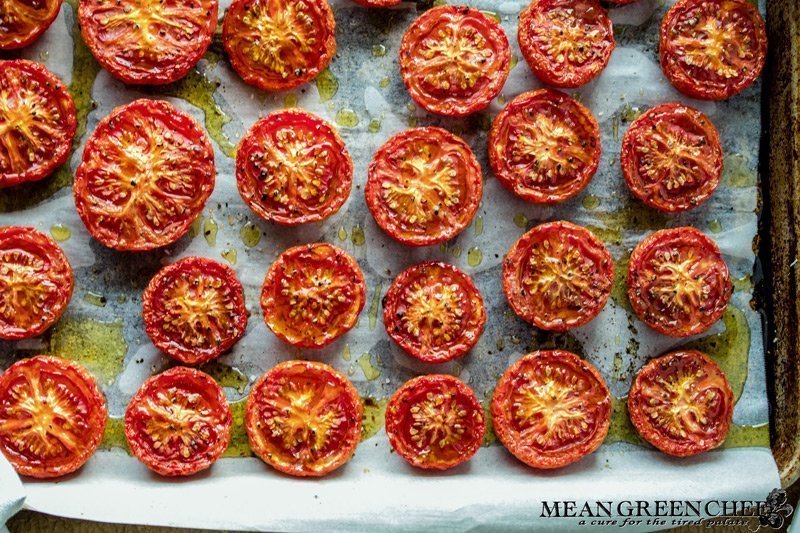 Slow Roasted Tomatoes on a sheet pan sitting in a sheet pan with parchment paper.