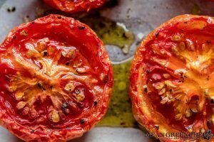 Close up of Sweet Slow Roasted Tomatoes on a sheet pan lined with parchment paper.