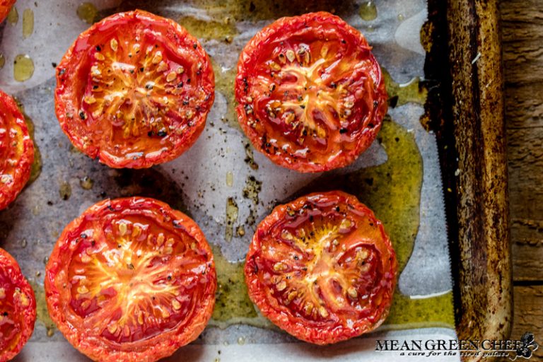 Sweet Slow Roasted Tomatoes on a sheet pan lined with parchment paper on a wooden background.