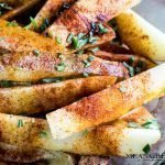 Potato wedges covered with olive oil, herbs and spices for oven baked fries.