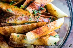 Potato wedges covered with olive oil, herbs and spices for oven baked fries.