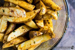 Potato wedges covered with olive oil, herbs and spices for oven baked fries.