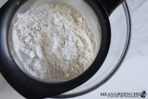 Flour, sea salt, and sugar being sifted for herbed crackers.