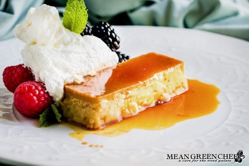 Flan on a white plate with berries and mint.