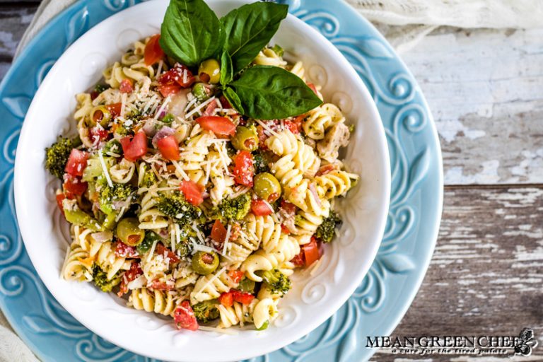 Italian Chicken Pasta Salad in a white bowl garnished with fresh basil.