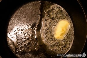 Butter sizzling in a cast iron pan that's ready to cook blackened chicken.