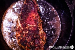 Blackened chicken finishing up cooking a cast iron pan.