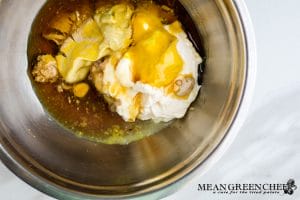 Ingredients for making Honey Mustard Dipping sauce in a metal bowl, just prior to mixing. Situated on a a white marble countertop.