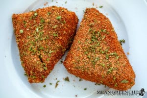 Two fillets of grouper coated with Badass Blackened Seasoning on a white plate, prepped and ready for cooking.