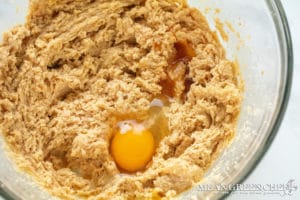 Meyer Lemon Cookie Dough in a glass bowl on a marble countertop, showing a creamy texture a single raw organic egg has been added for mixing.