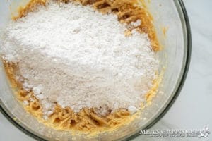 Meyer Lemon Cookie Dough in a glass bowl on a marble countertop, showing a creamy texture, flour has been added on top for incorporating into the dough.