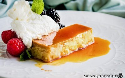 Flan on a white plate with berries and mint.